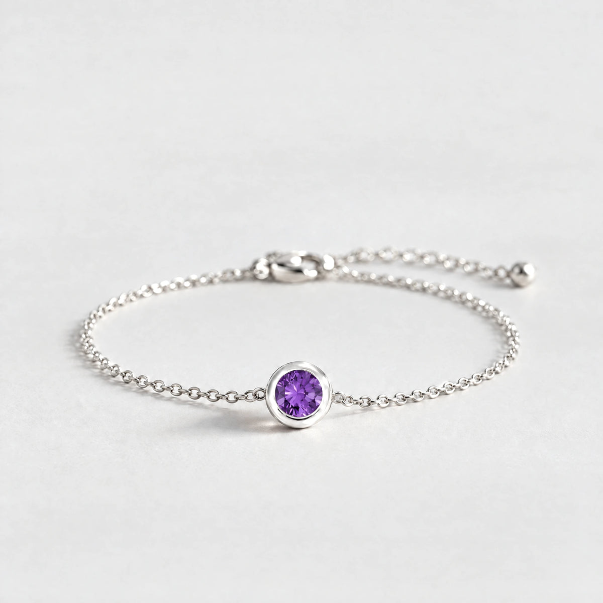 Silver Zara Birthstone Charm Bracelet with amethyst violet February birthstone-color crystal on a light grey background
