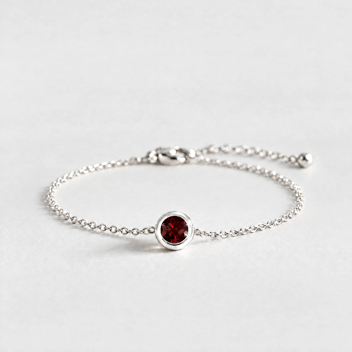 Silver Zara Birthstone Charm Bracelet with garnet red January birthstone-color crystal on a light grey background