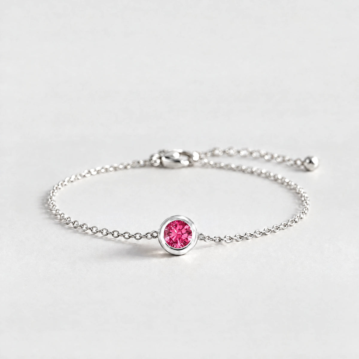 Silver Zara Birthstone Charm Bracelet with ruby rose July birthstone-color crystal on a light grey background