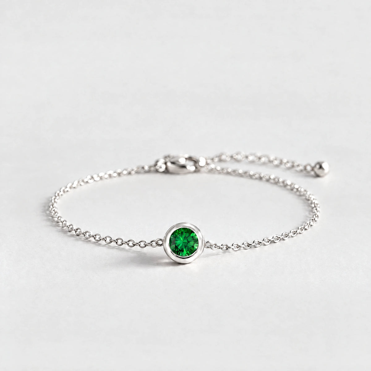 Silver Zara Birthstone Charm Bracelet with emerald green May birthstone-color crystal on a light grey background