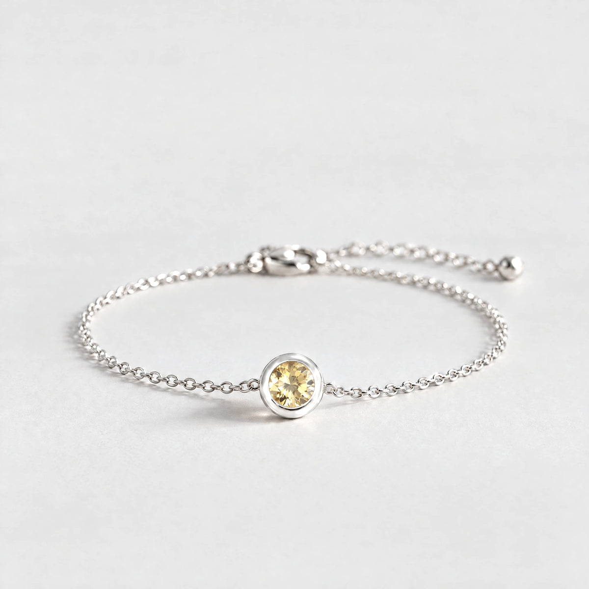 Silver Zara Birthstone Charm Bracelet with citrine champagne November birthstone-color crystal on a light grey background